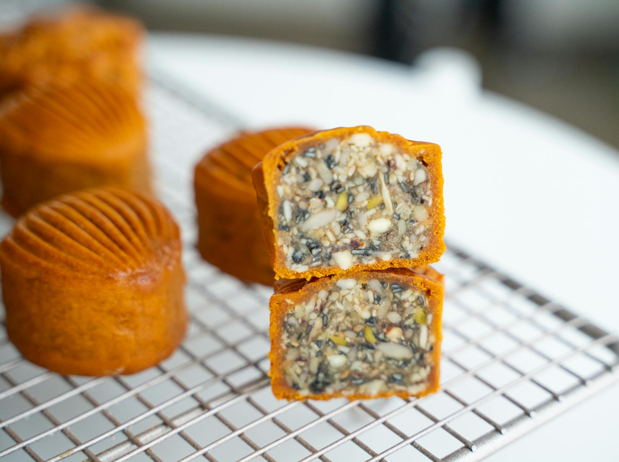 A detailed view of cut traditional Chinese mooncakes filled with seeds and nuts on a cooling rack.