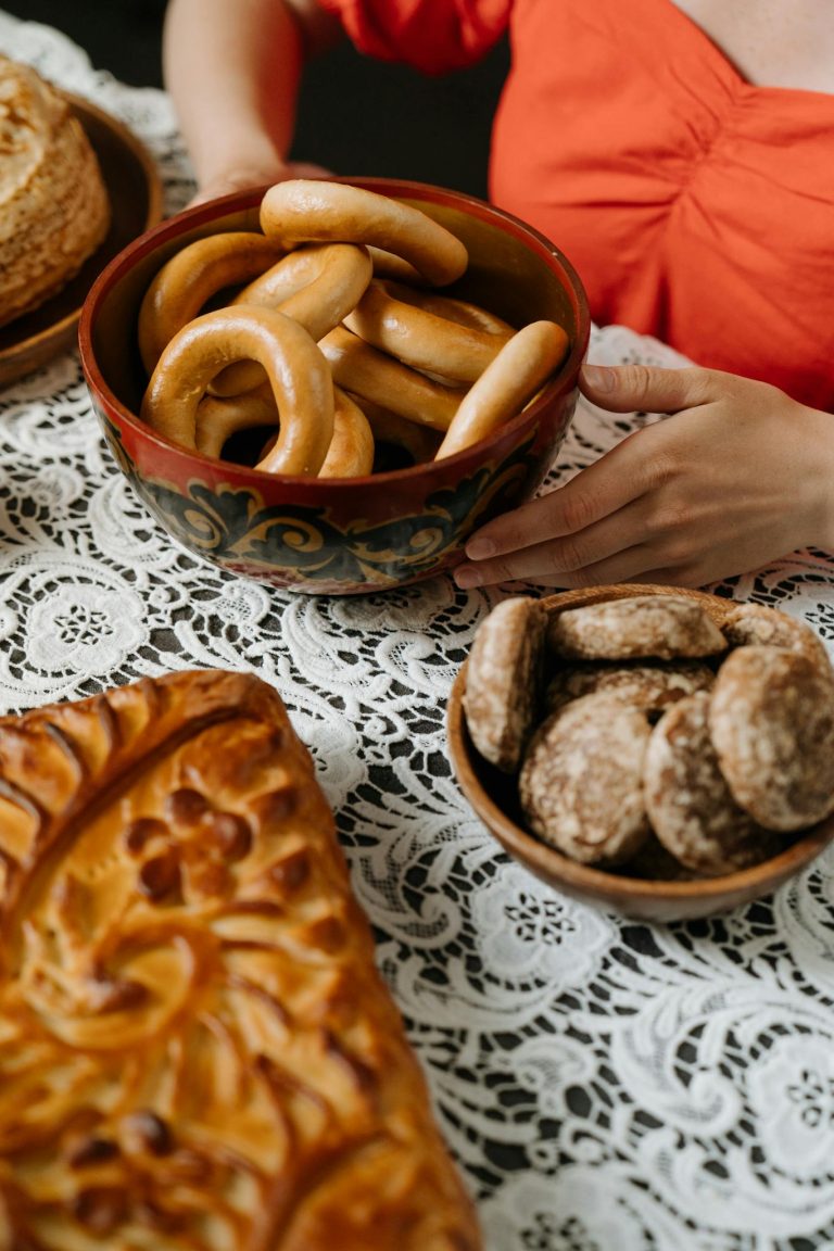A display of traditional Russian baked goods on a lace tablecloth, featuring barankas and pastries.