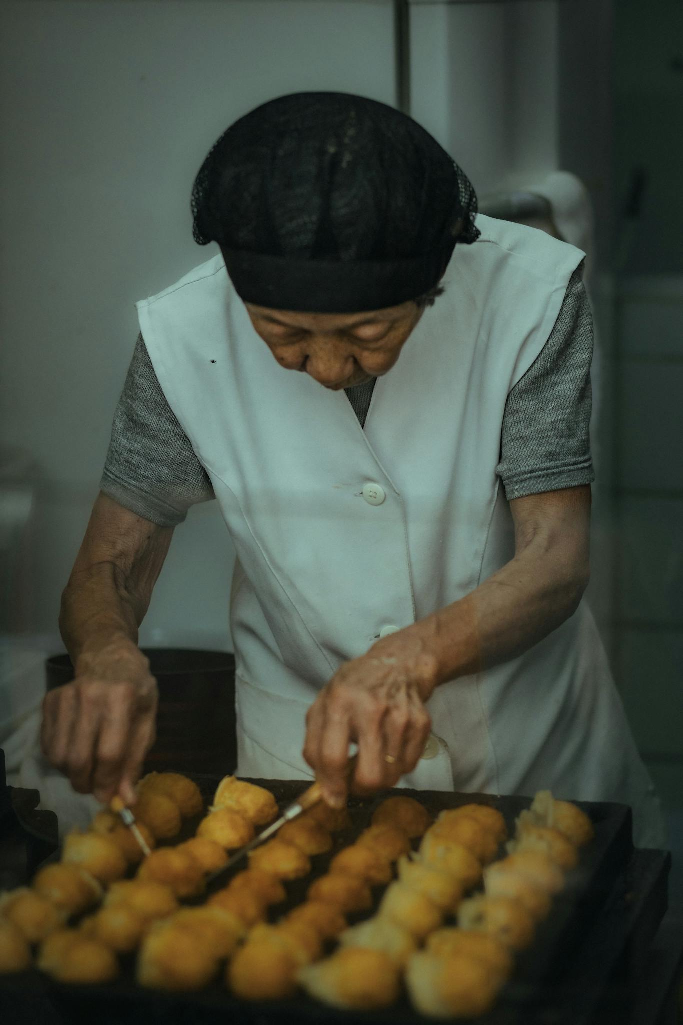 Elderly woman baking pastries, showcasing culinary tradition and craftsmanship.